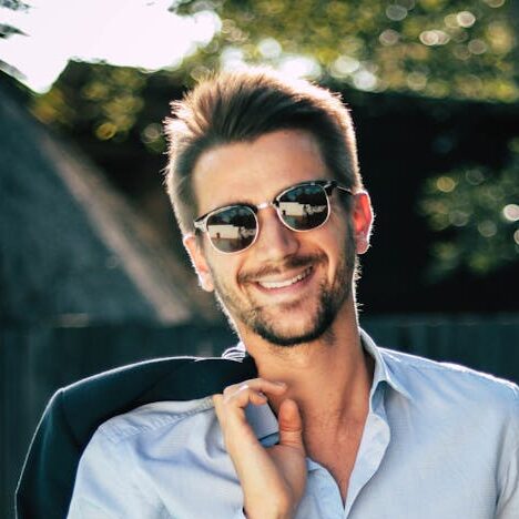 Photo by Chloe Confident young man in a stylish suit outdoors, exuding charm and elegance.